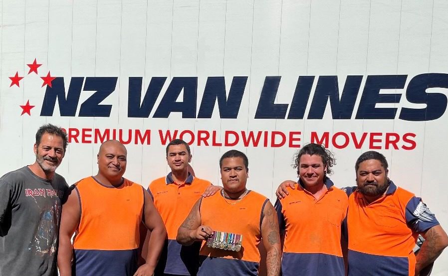 employees at nz van lines in front of logo
