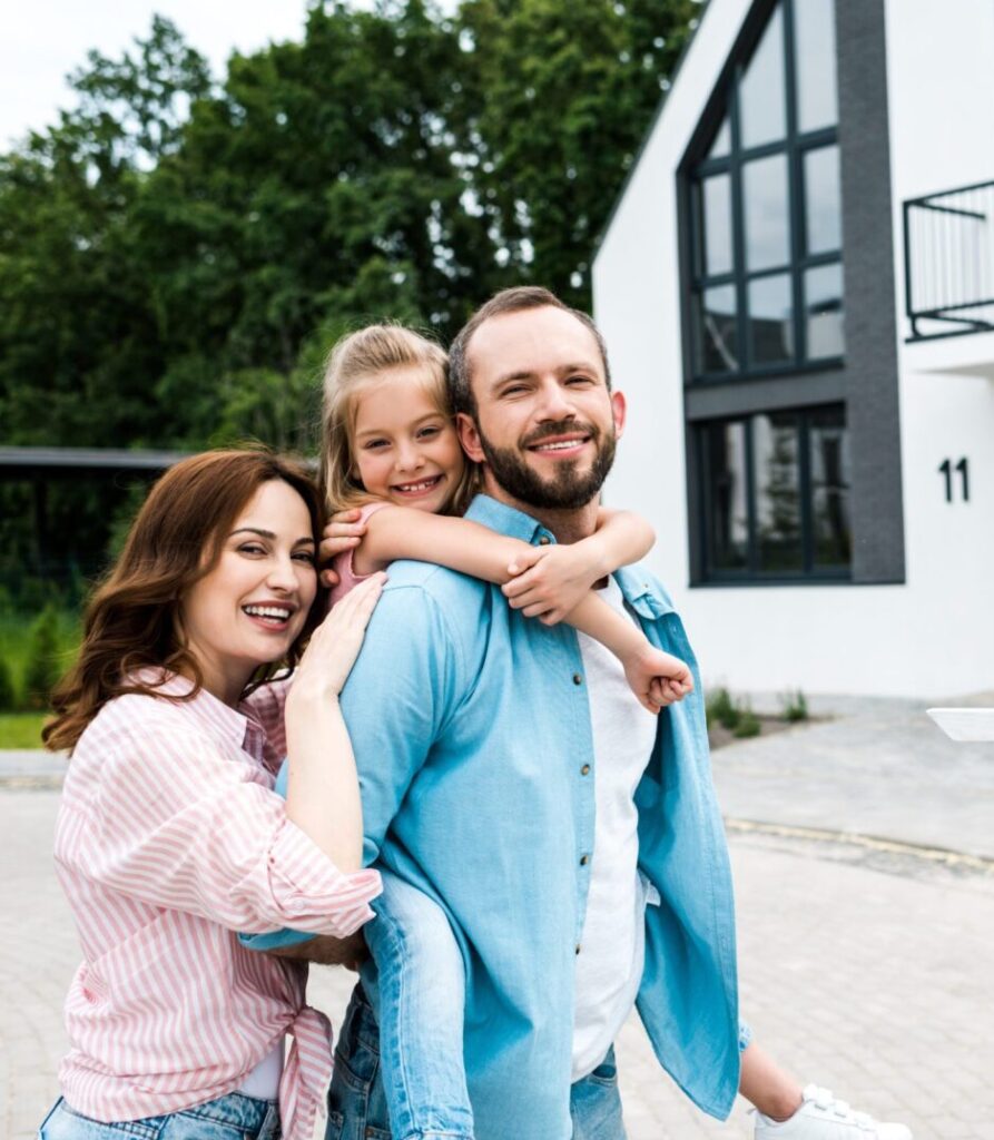 happy bearded man piggybacking daughter near cheerful wife and board with sold letters